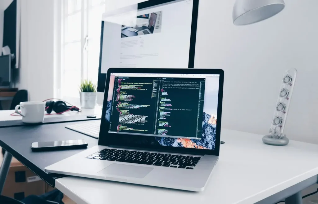 A laptop showing code beside a website on a second screen